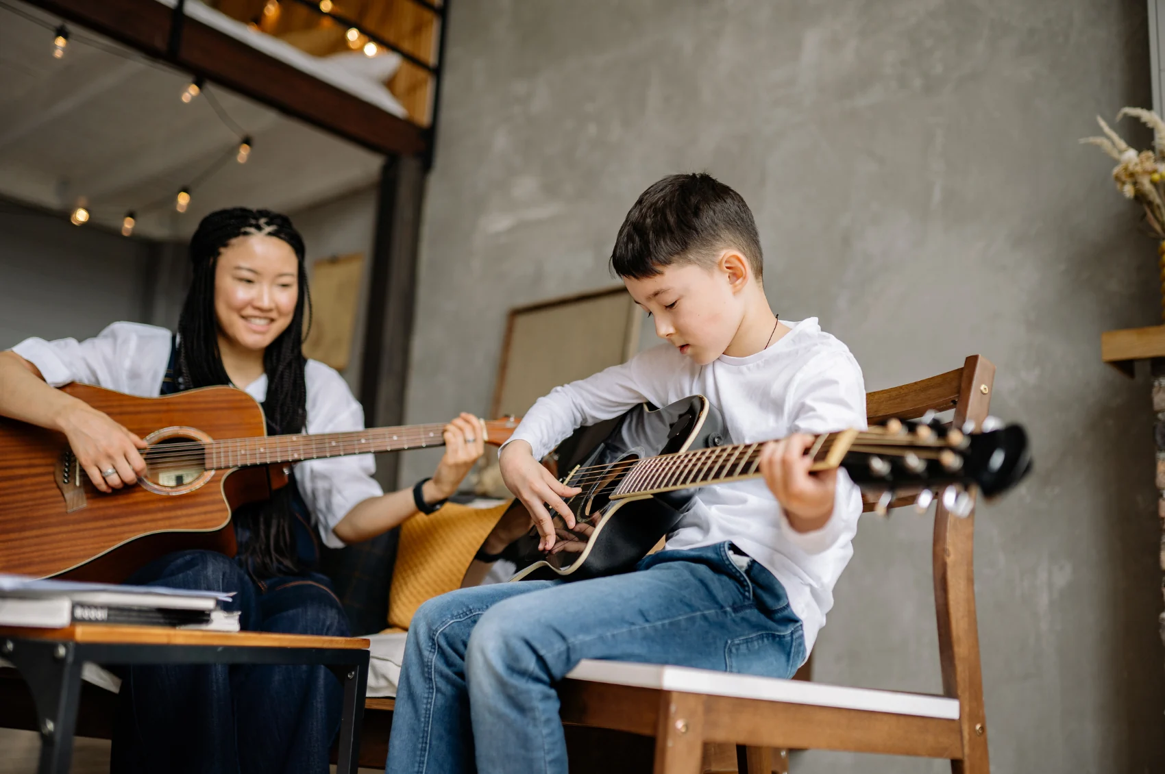 Guitar teacher and young student practicing together