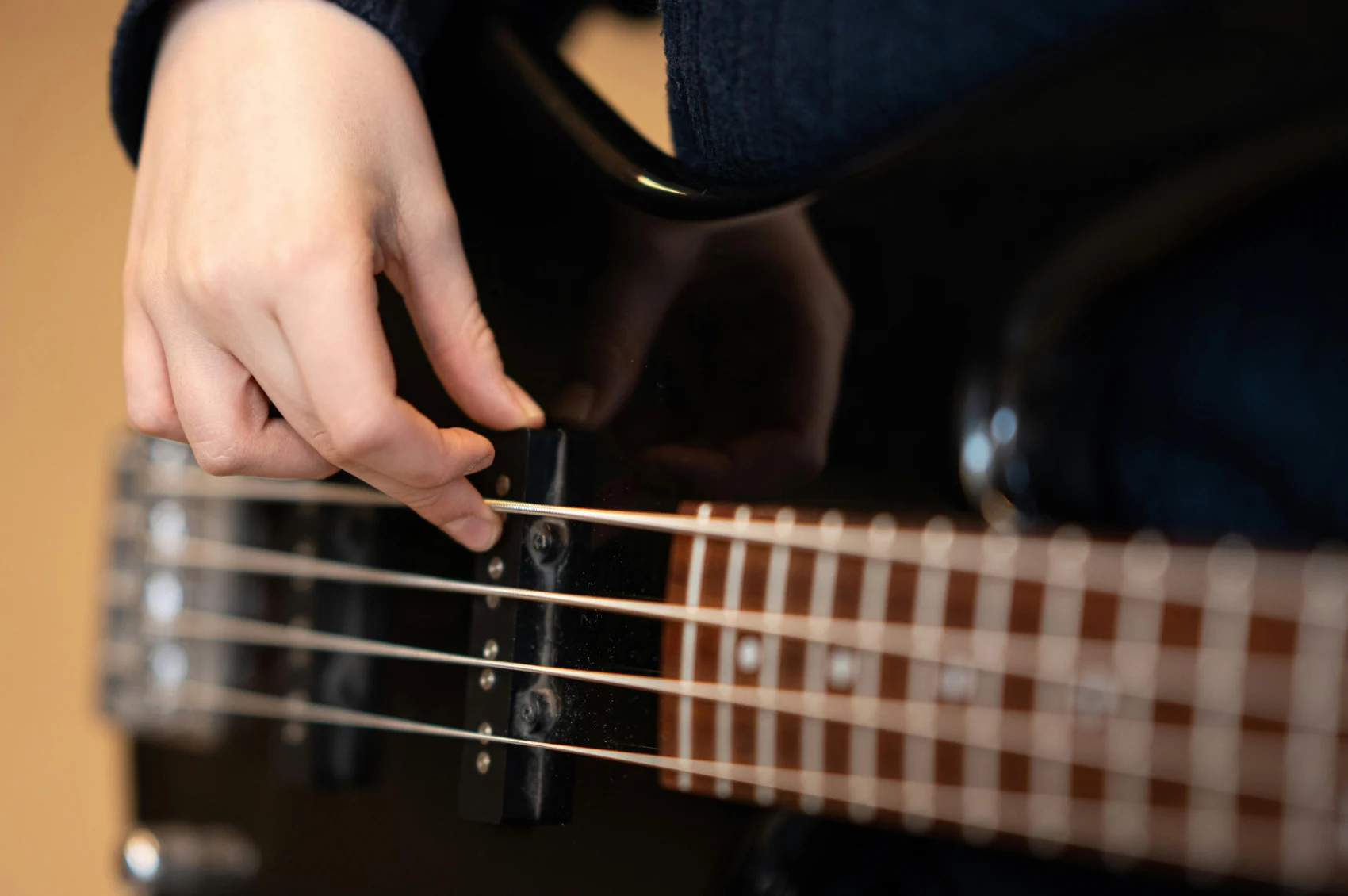 A musician plucking the strings of an electric bass