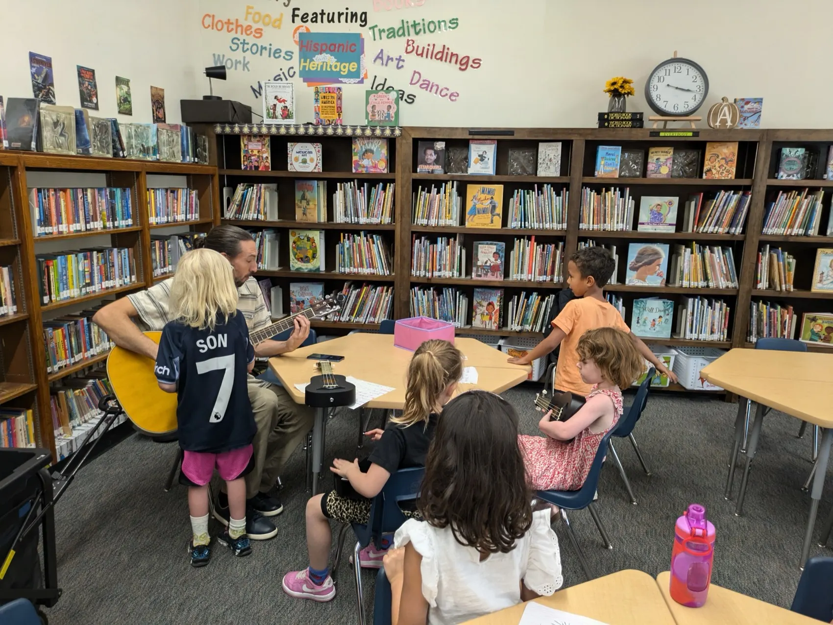 Children learning ukulele with their teacher in a school library