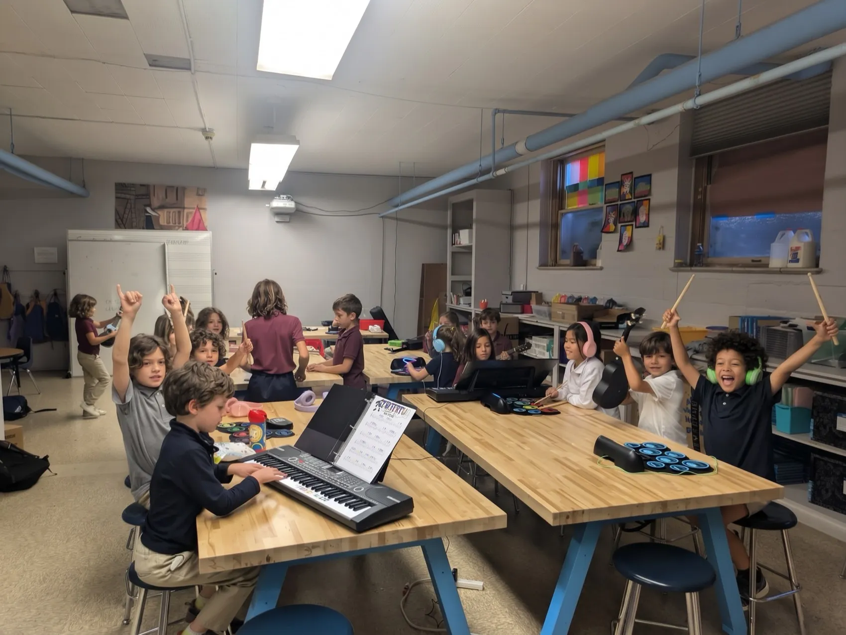 Children cheering with drumsticks in an after-school music class with keyboards and drum pads