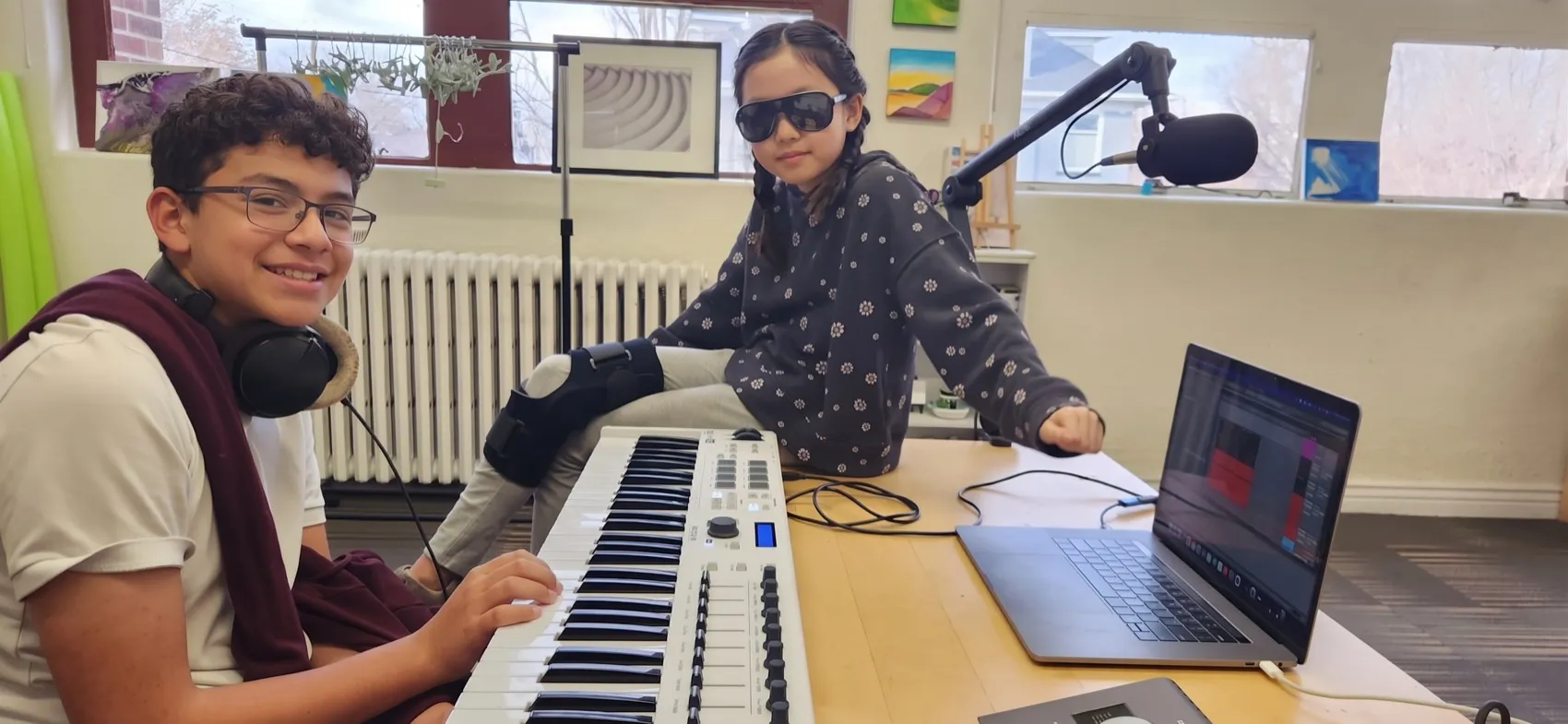 Two students making music with a keyboard, microphone and laptop during a Music 4 Humans class