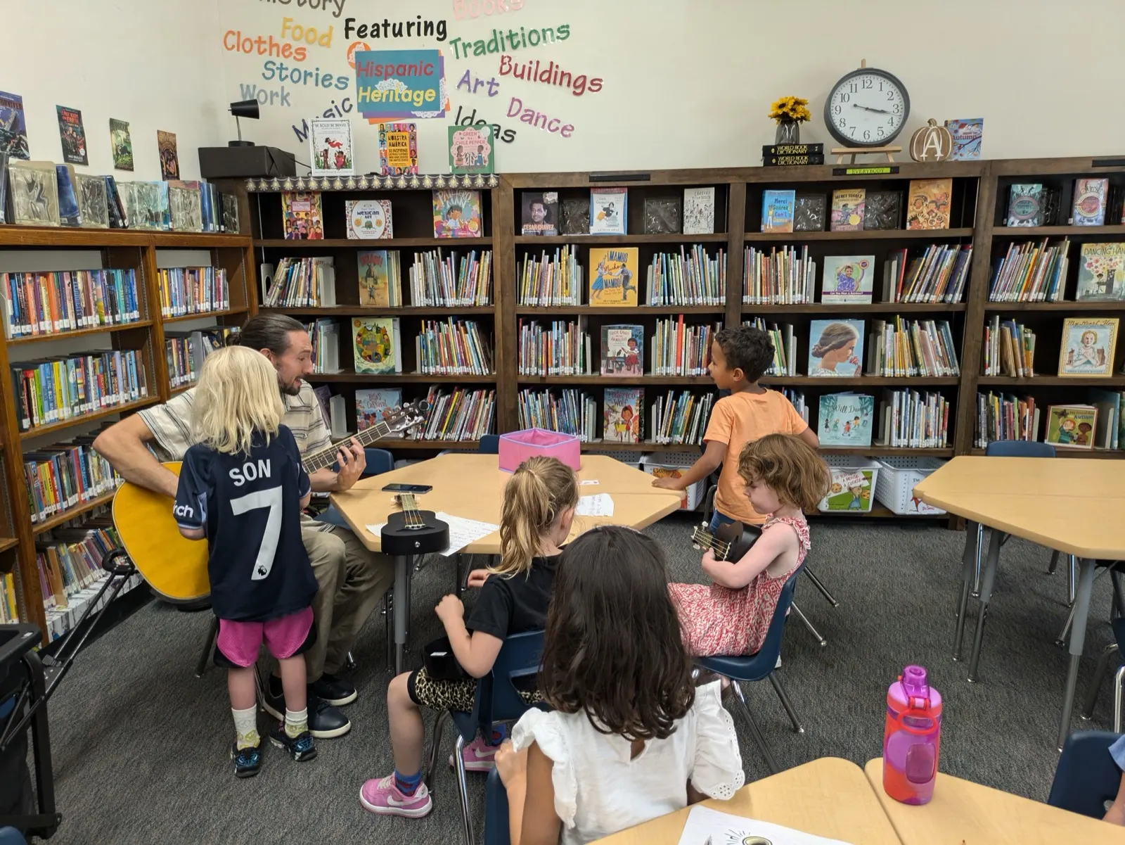 A Music 4 Humans teacher playing guitar with children during an after-school class in a school library