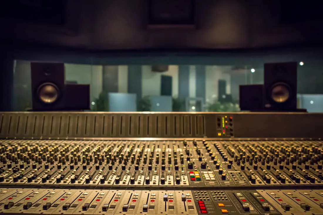 The control room at the Music 4 Humans studio in southwest Denver, looking across a mixing console and through the glass into the live room