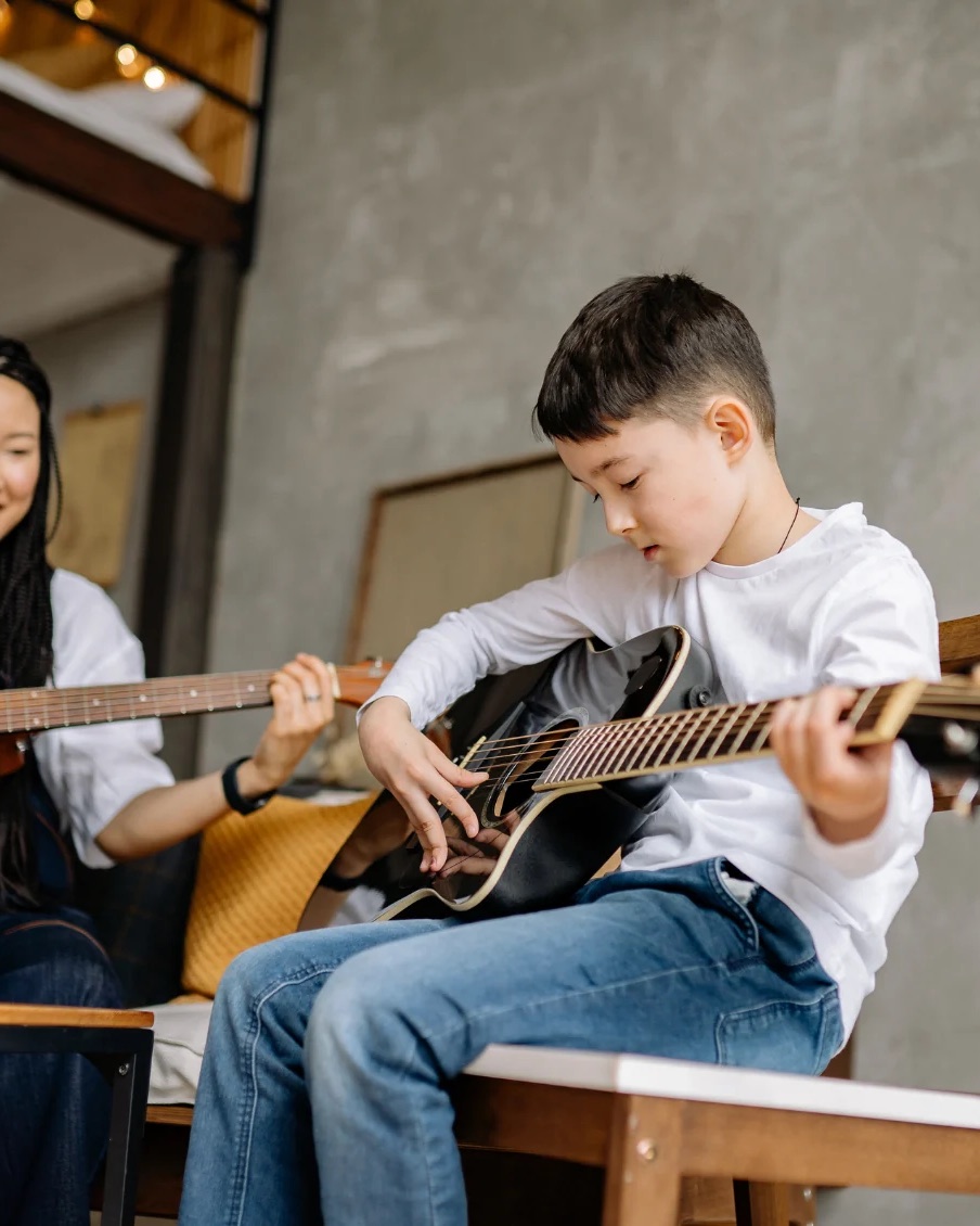 A guitar teacher and a young student playing together
