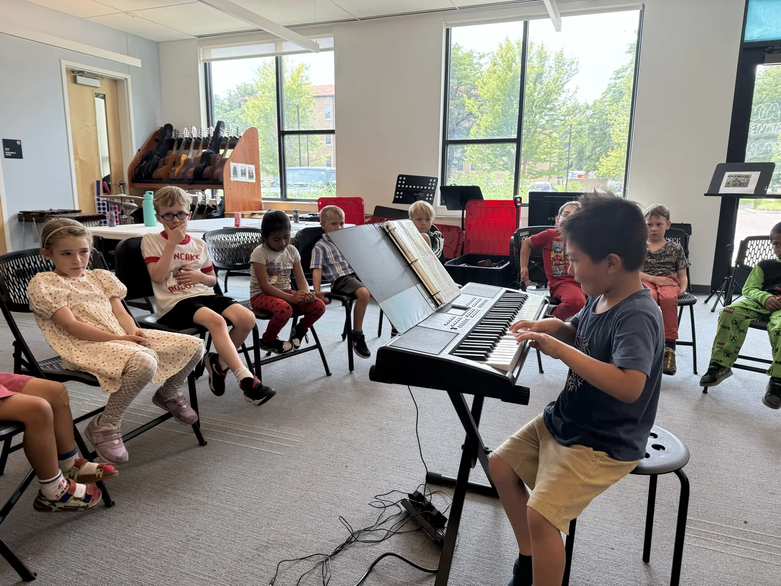 A student playing keyboard for classmates sitting in a circle