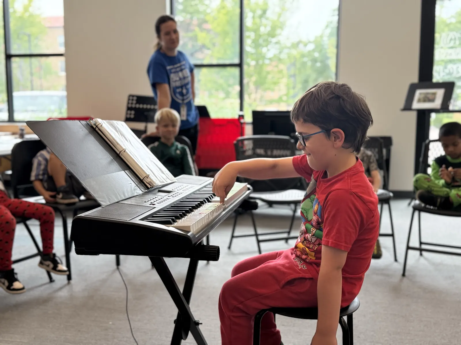 A boy smiling as he plays keyboard in front of his class