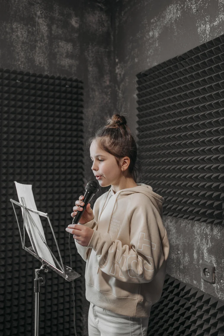 A young singer practicing with a microphone and sheet music